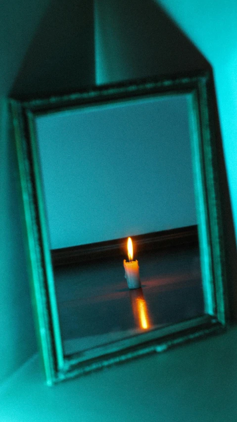 a small lighted candle is in the mirror