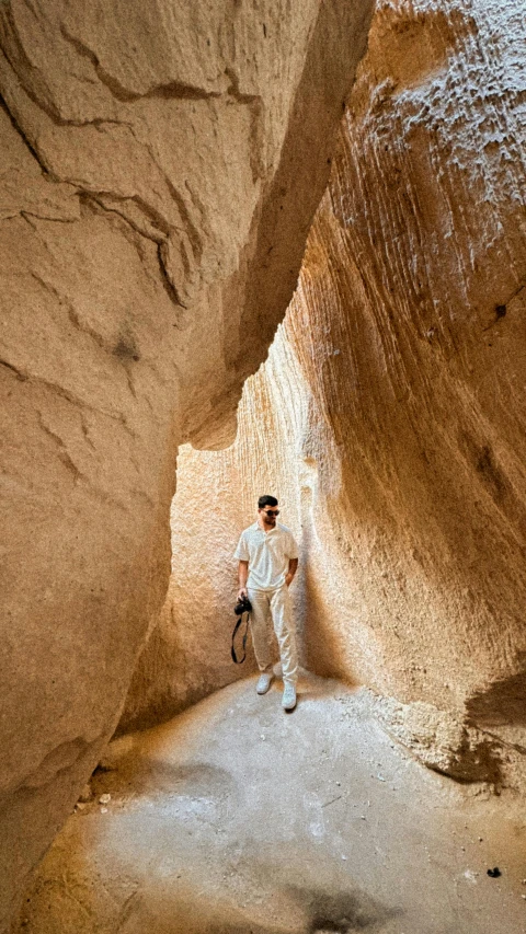 man standing in an eroded slot between two other cliffs