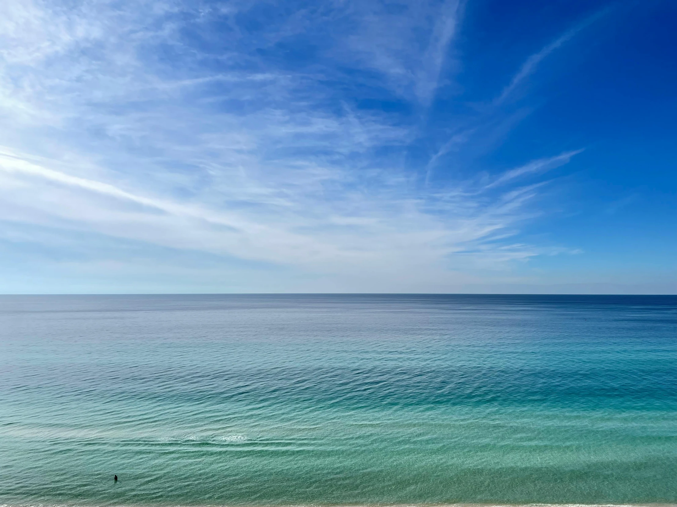 a blue ocean with clouds above and a white boat in the water