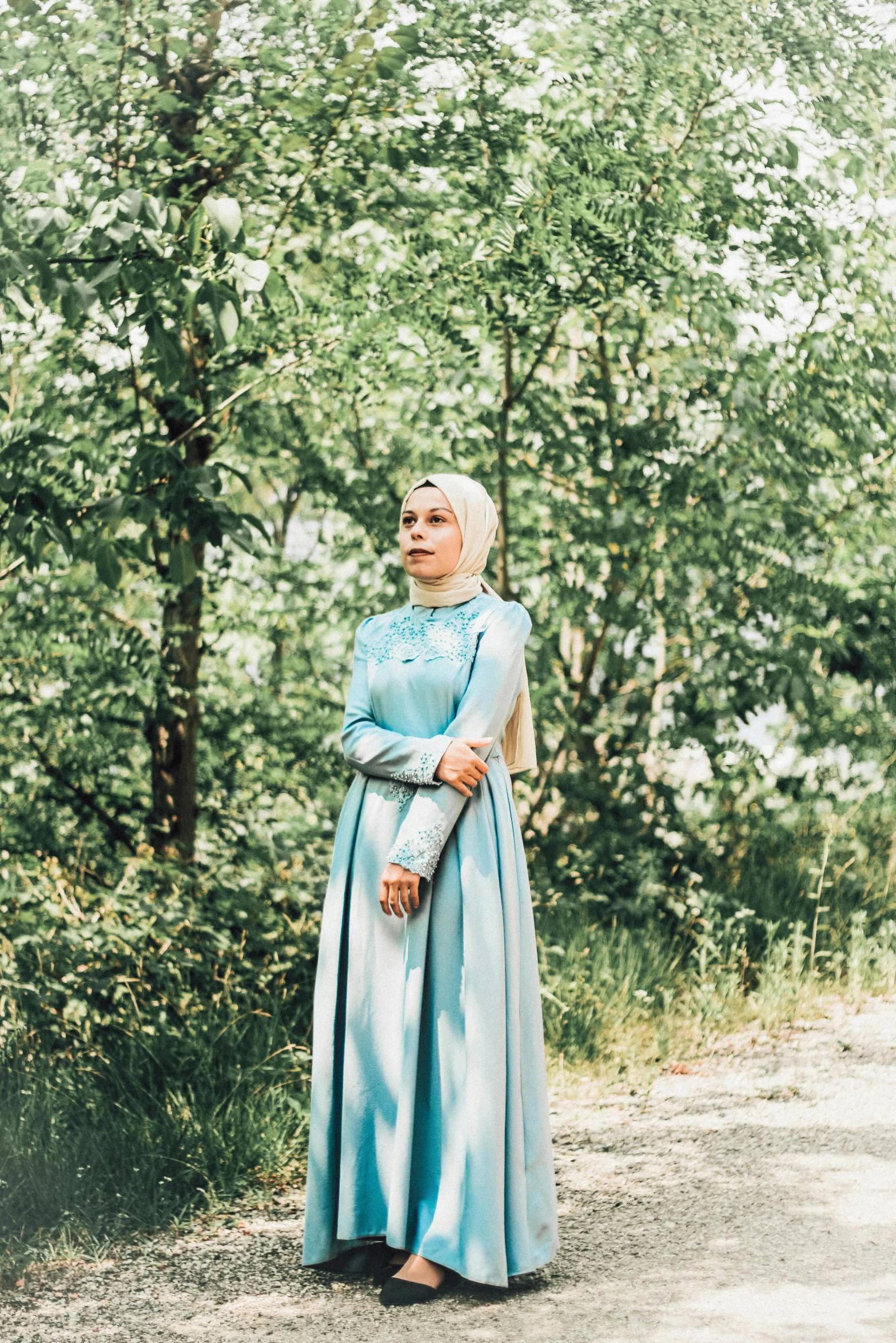 a woman standing outside in an old fashioned blue dress