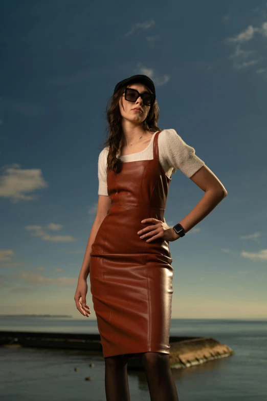 a woman standing in front of the ocean wearing a brown leather apron