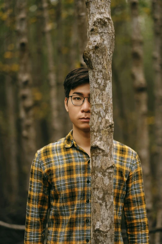 a man standing against a tree looking down