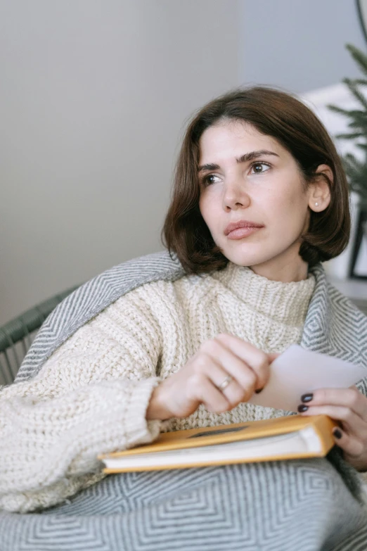 a girl reading a book while sitting in a chair