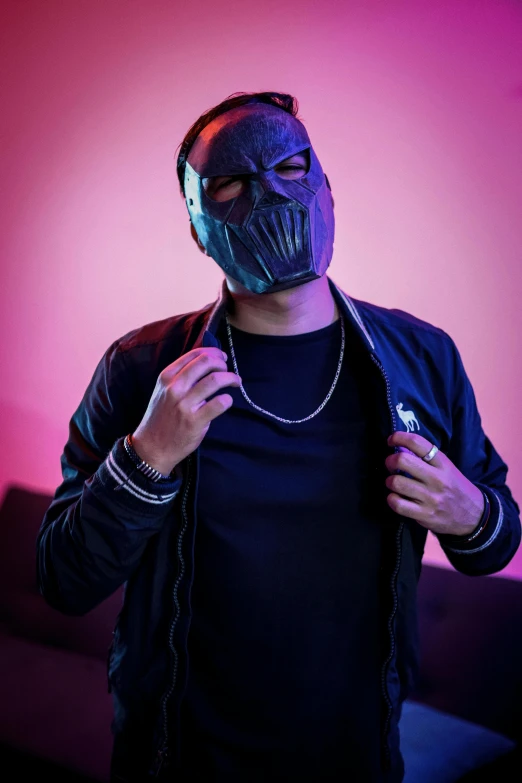 a man in a black mask poses against a purple background