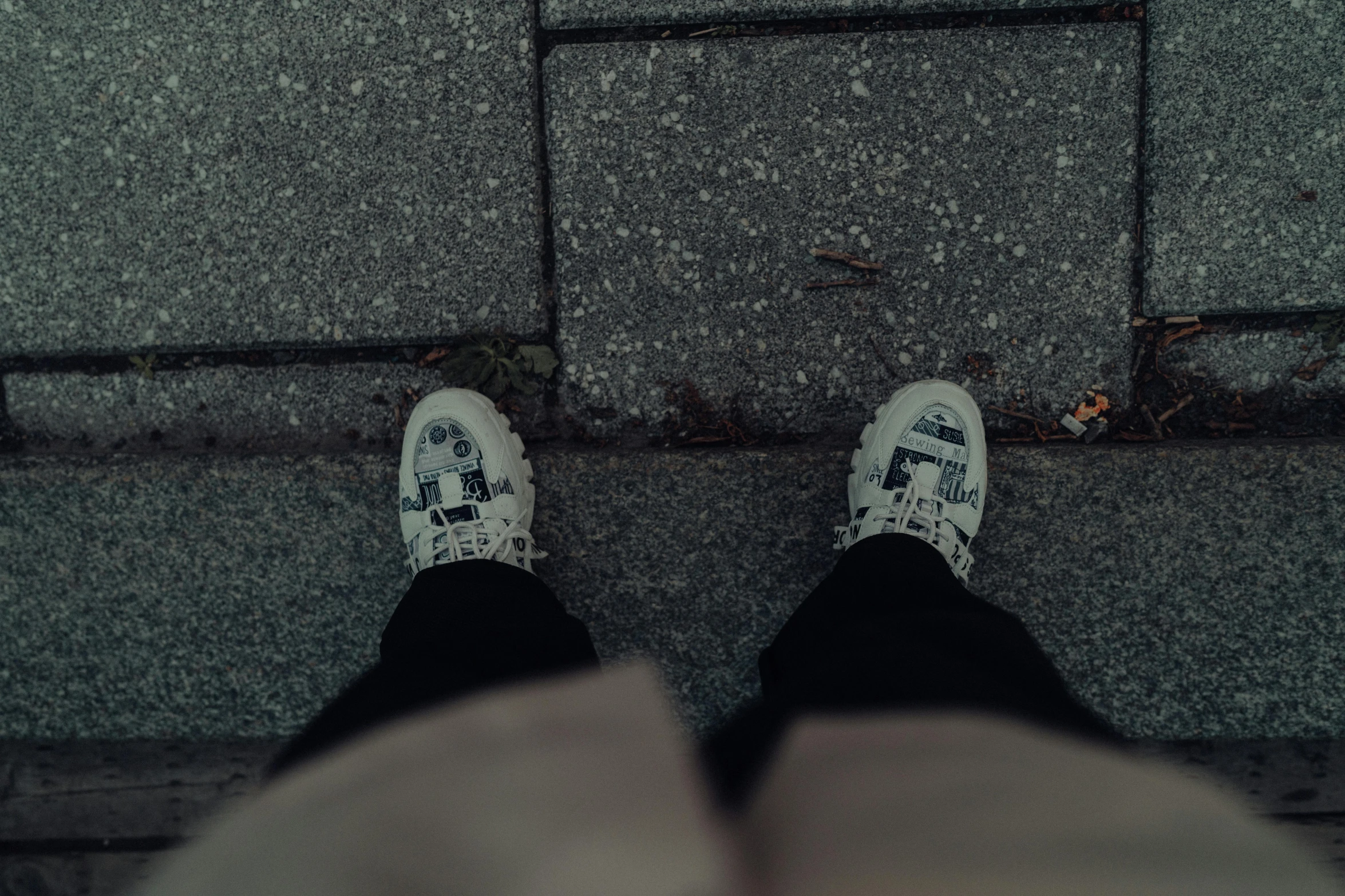 a pair of feet standing on the pavement with the street