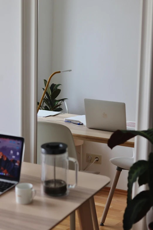 an open laptop on a wooden table near a plant