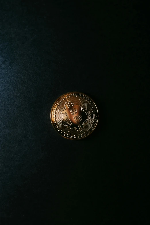 a small golden coin sitting on a black surface