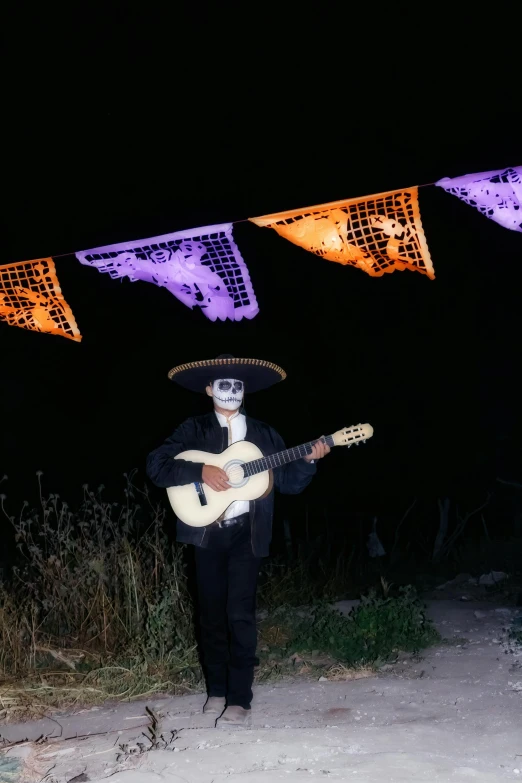 a man with a mexican - themed hat holding a guitar at night