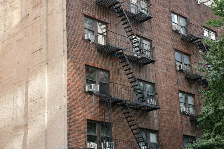 multiple fire escapes in a brick building between two windows