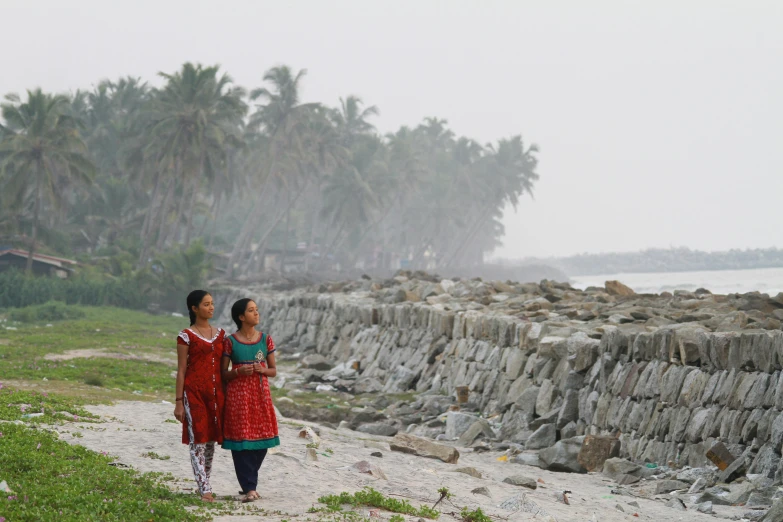 two women walking along side a rocky beach