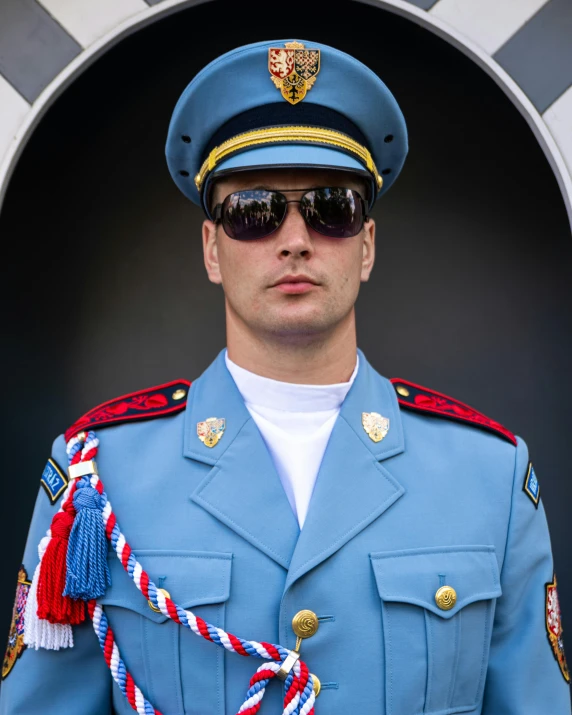 man in blue uniform posing in front of doorway with rope