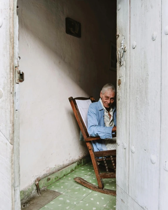 an old man with beard is sitting in the door way