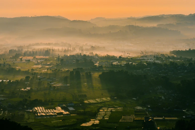 a view of a misty hillside with mountains in the background