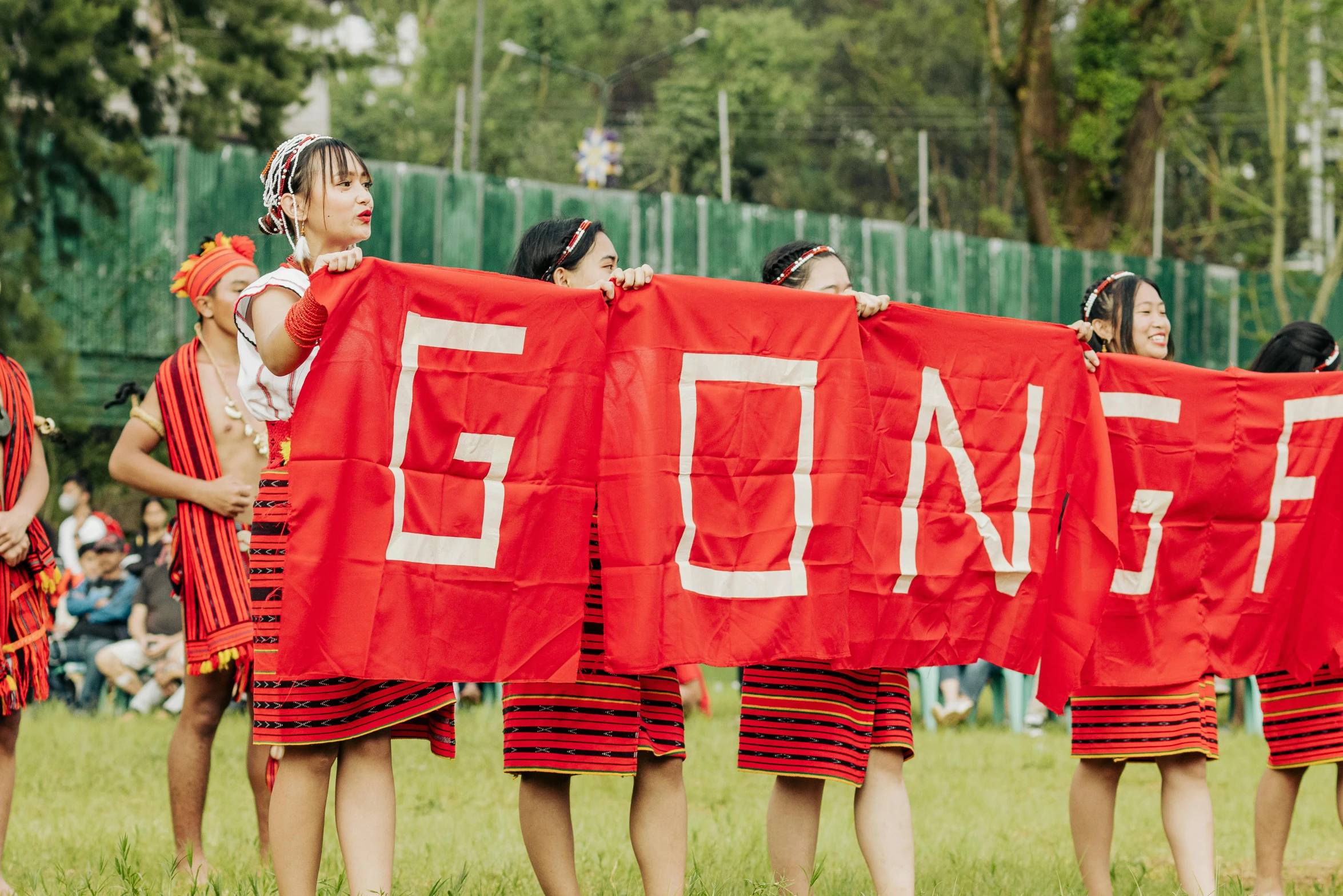 a group of girls stand together holding a red banner