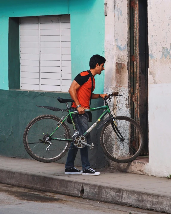 a man walking a bike down the street while holding it on his back