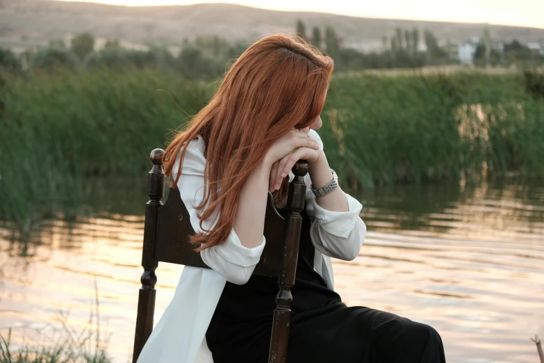 woman sitting on a chair in front of a body of water