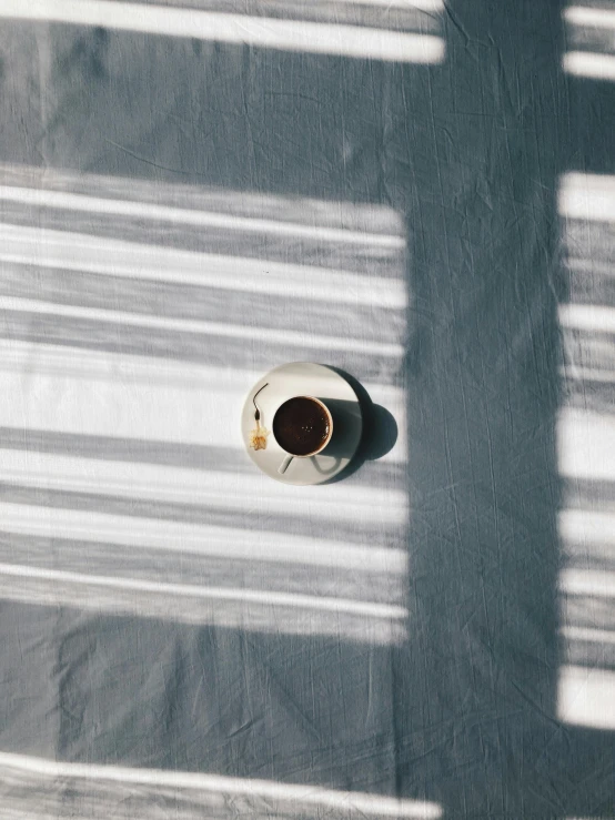 a coffee cup on a white plate with some shadows