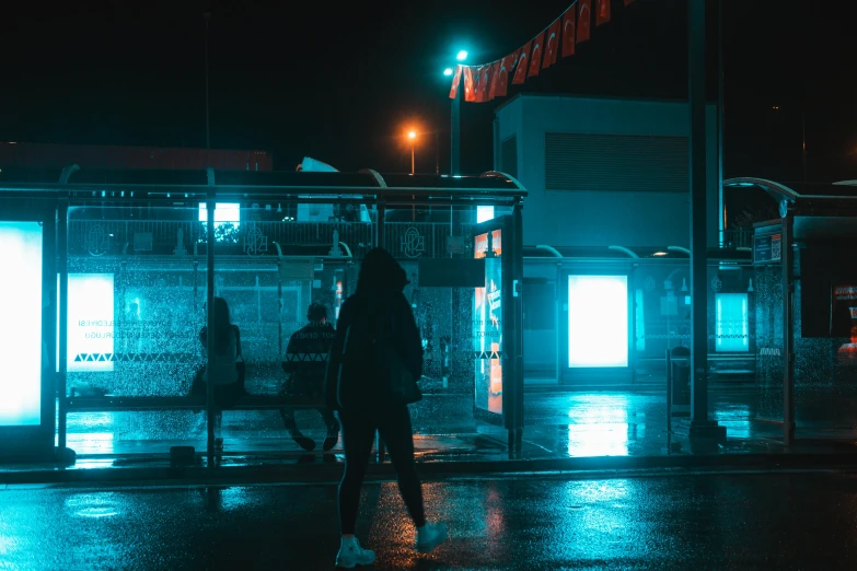 people standing on the sidewalk in front of a shop at night