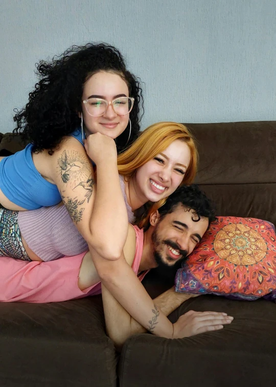 two girls on a couch, one holding a pillow with her arm around the other