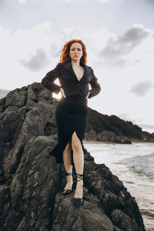 a woman posing on some rocks with her hand on her hips