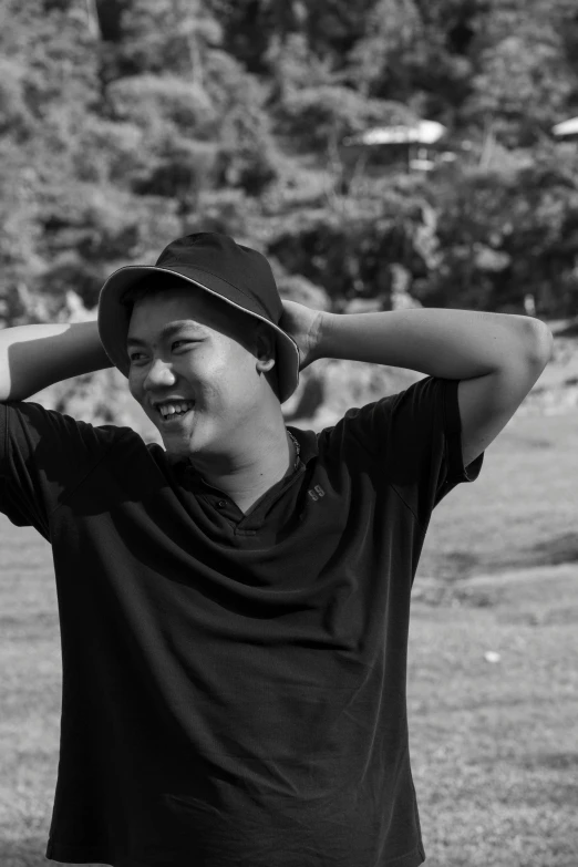 a young man holds his hat behind his head