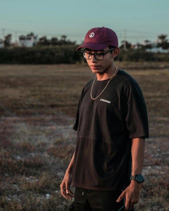 a man standing in an empty field wearing a hat