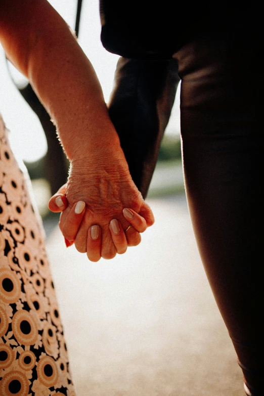 a couple is holding hands as they walk towards the camera