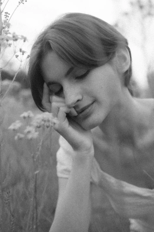 a beautiful woman standing in a field while talking on a cell phone