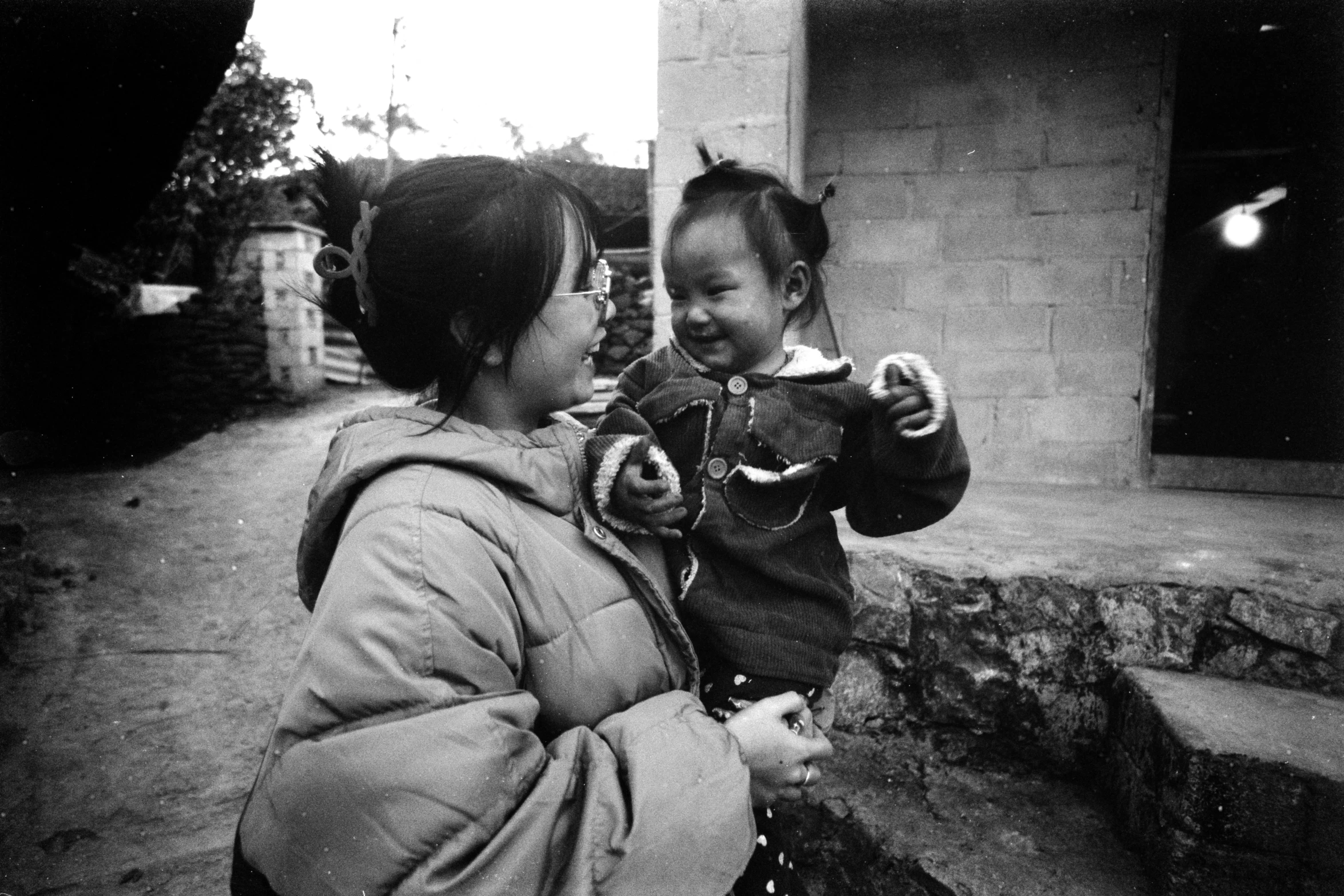 a little girl standing by her mother in the street