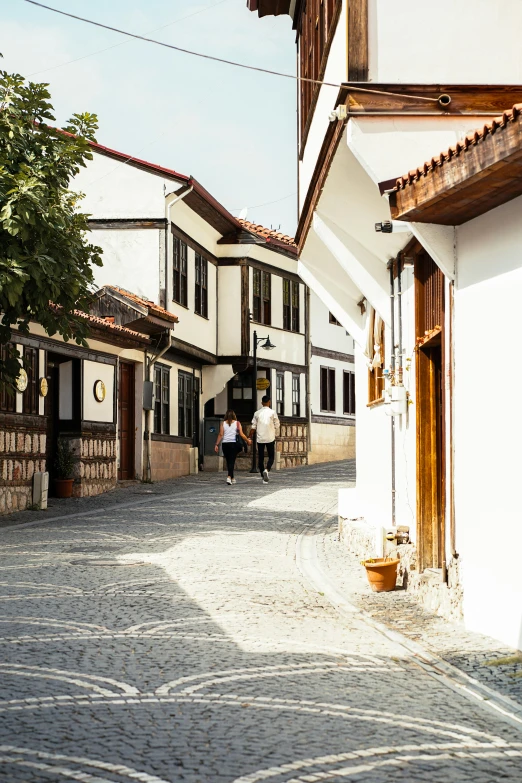 a couple of people walking down a street next to houses