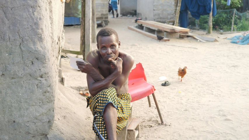 a boy in africa sitting down and holding a cellphone