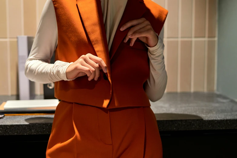 a woman in an orange vest stands near a stove