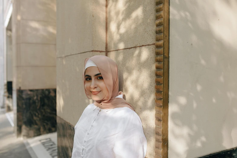 a woman wearing a headscarf standing near a building