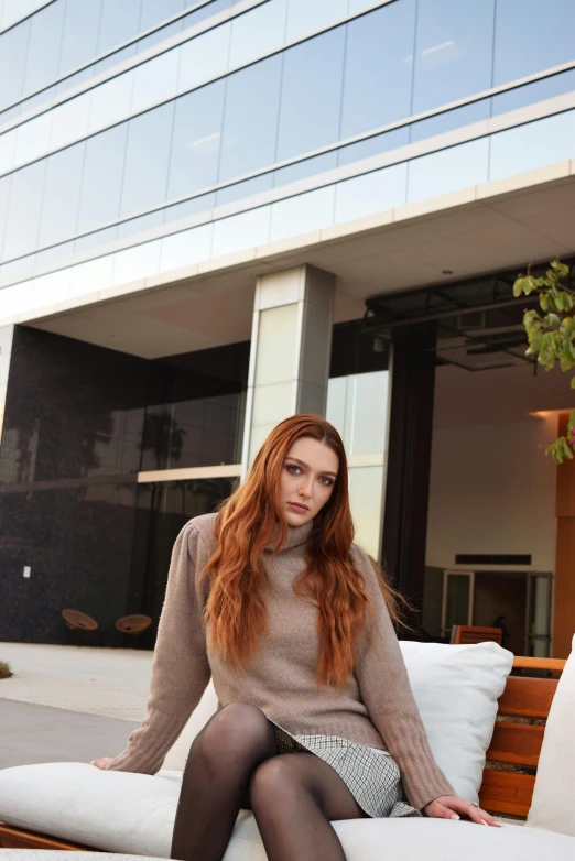 a young woman sitting on a couch in front of a building