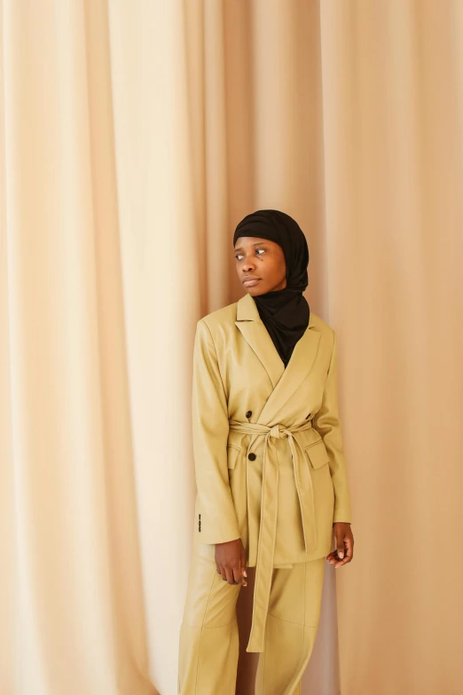 a woman in a yellow jacket standing against a wall