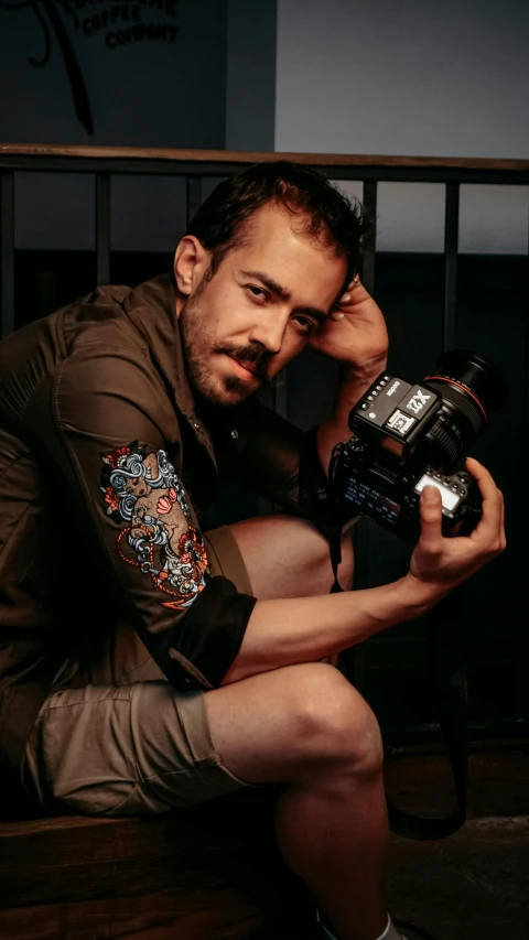 a man sits down holding a camera while posing for a picture