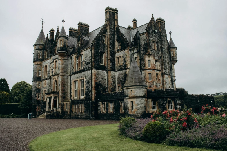 a big stone castle that has many flowers in front of it