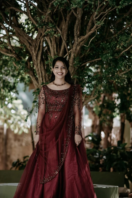 a woman standing in front of trees in a dress