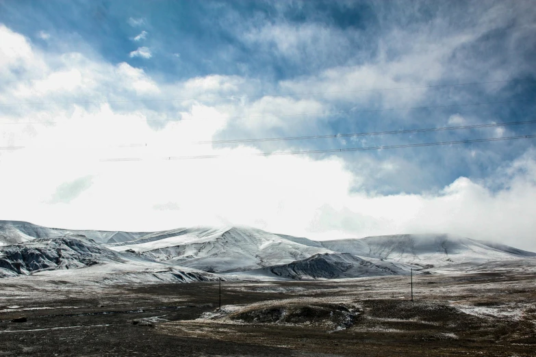 view of hills and power lines near the snow covered mountain range