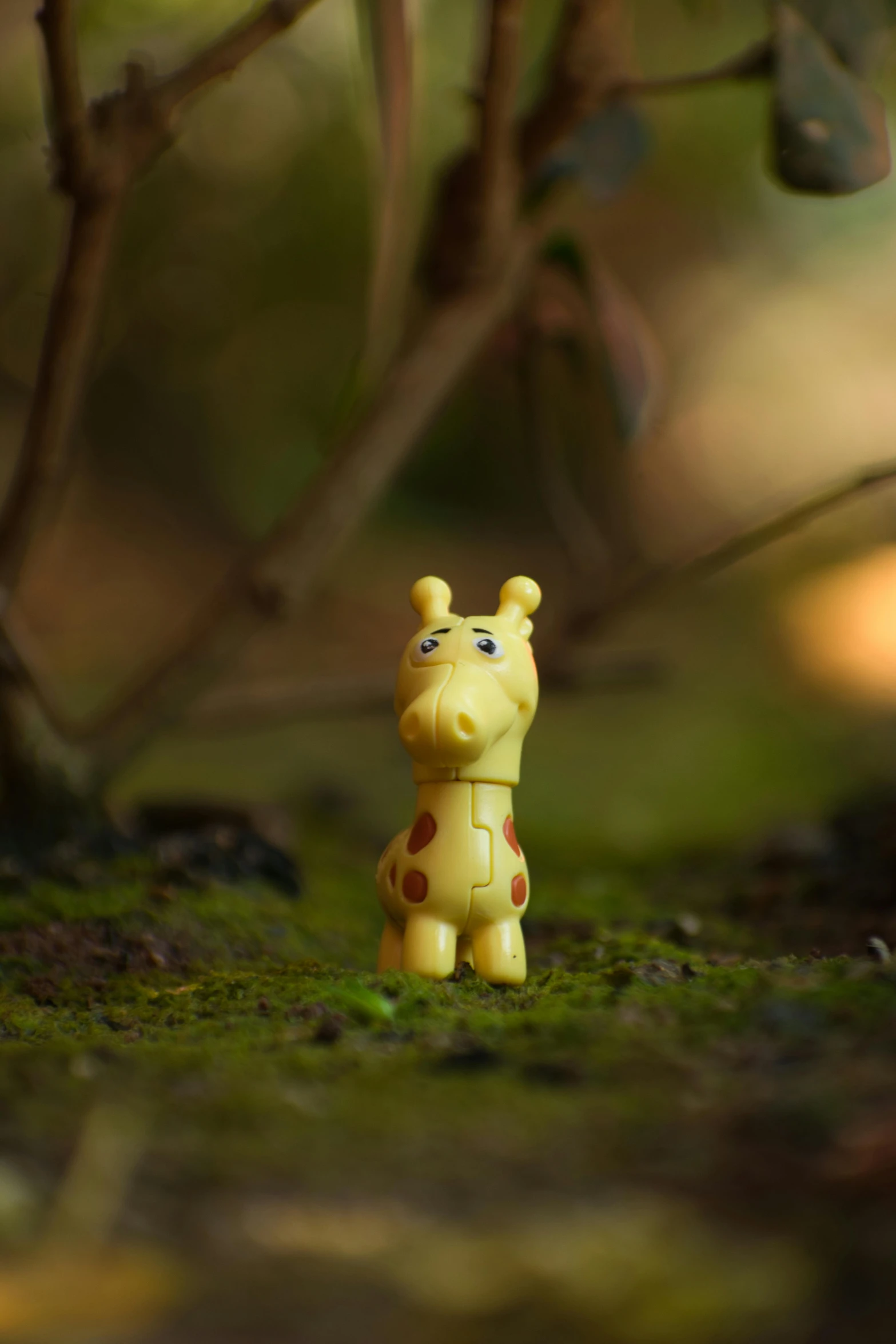 a little yellow giraffe toy sitting in the grass