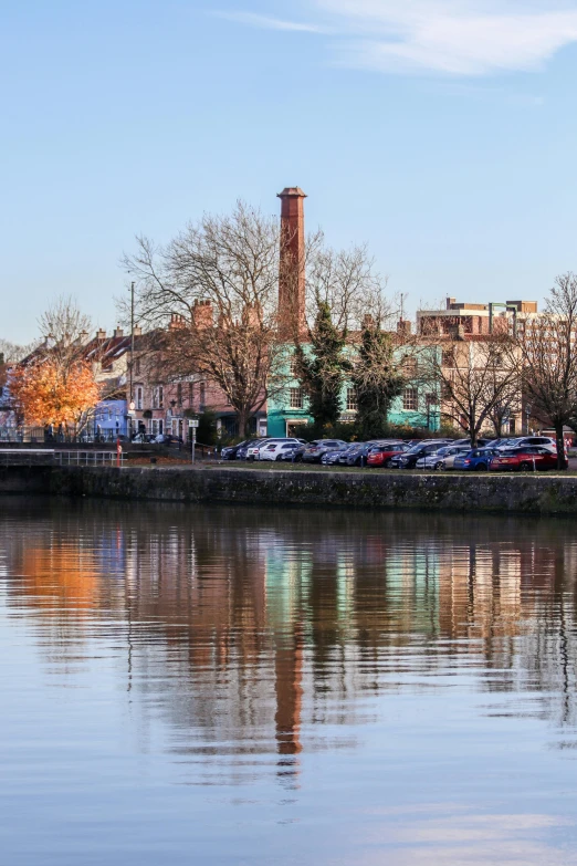 a clock tower stands above the water in front of some buildings