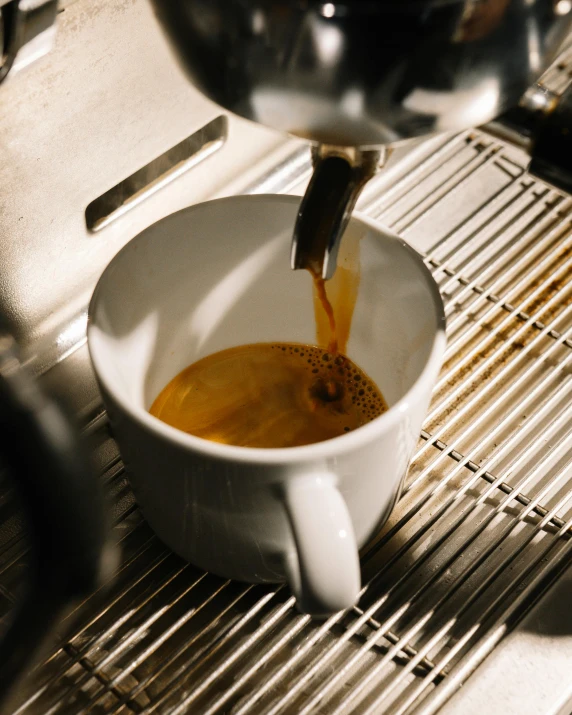 there is coffee being made in a white cup