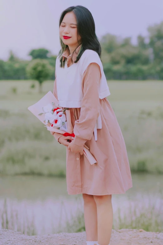 a woman is holding a bouquet near a body of water