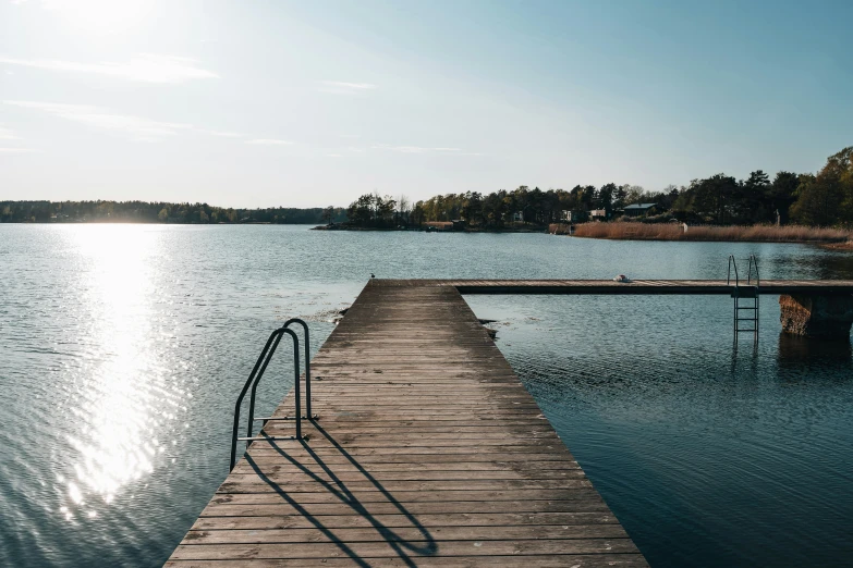 the dock stretches out into the water while the sun reflects in the water