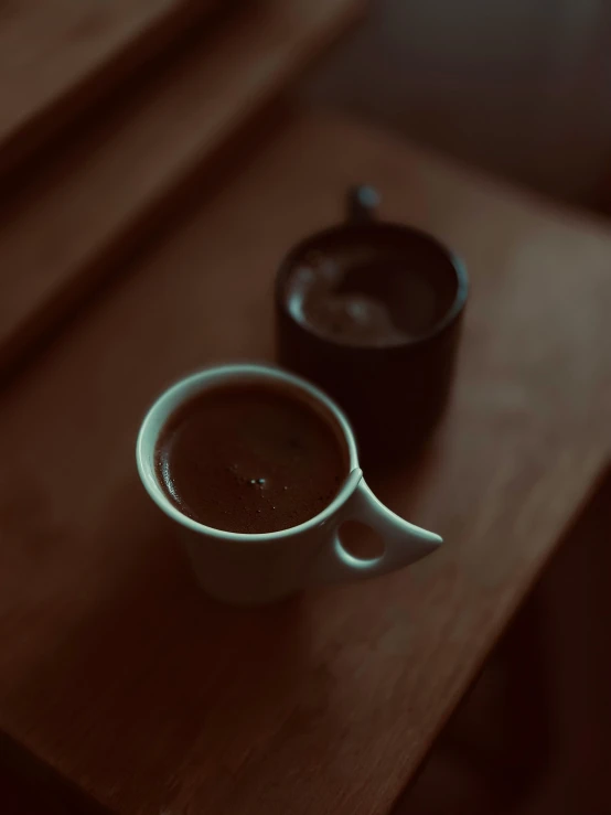 two cups of chocolate coffee sitting on a table