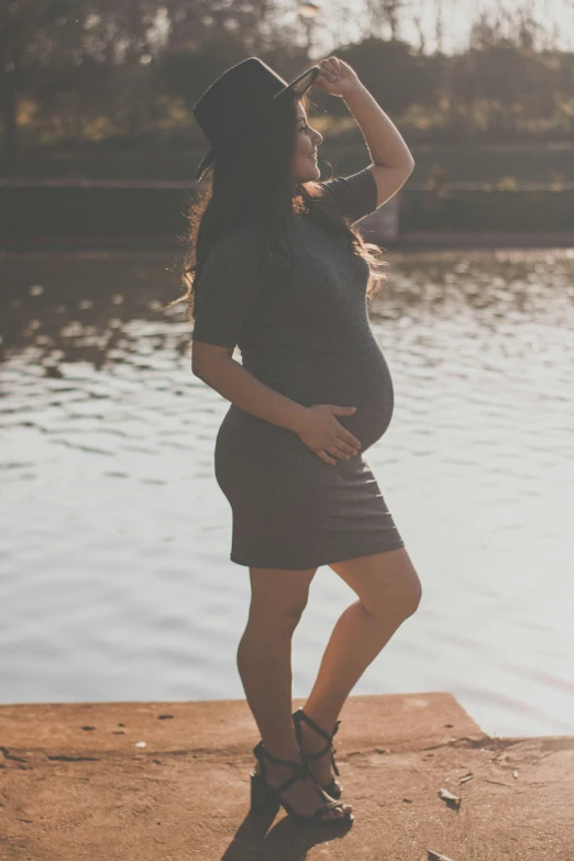 pregnant woman in black dress near the water