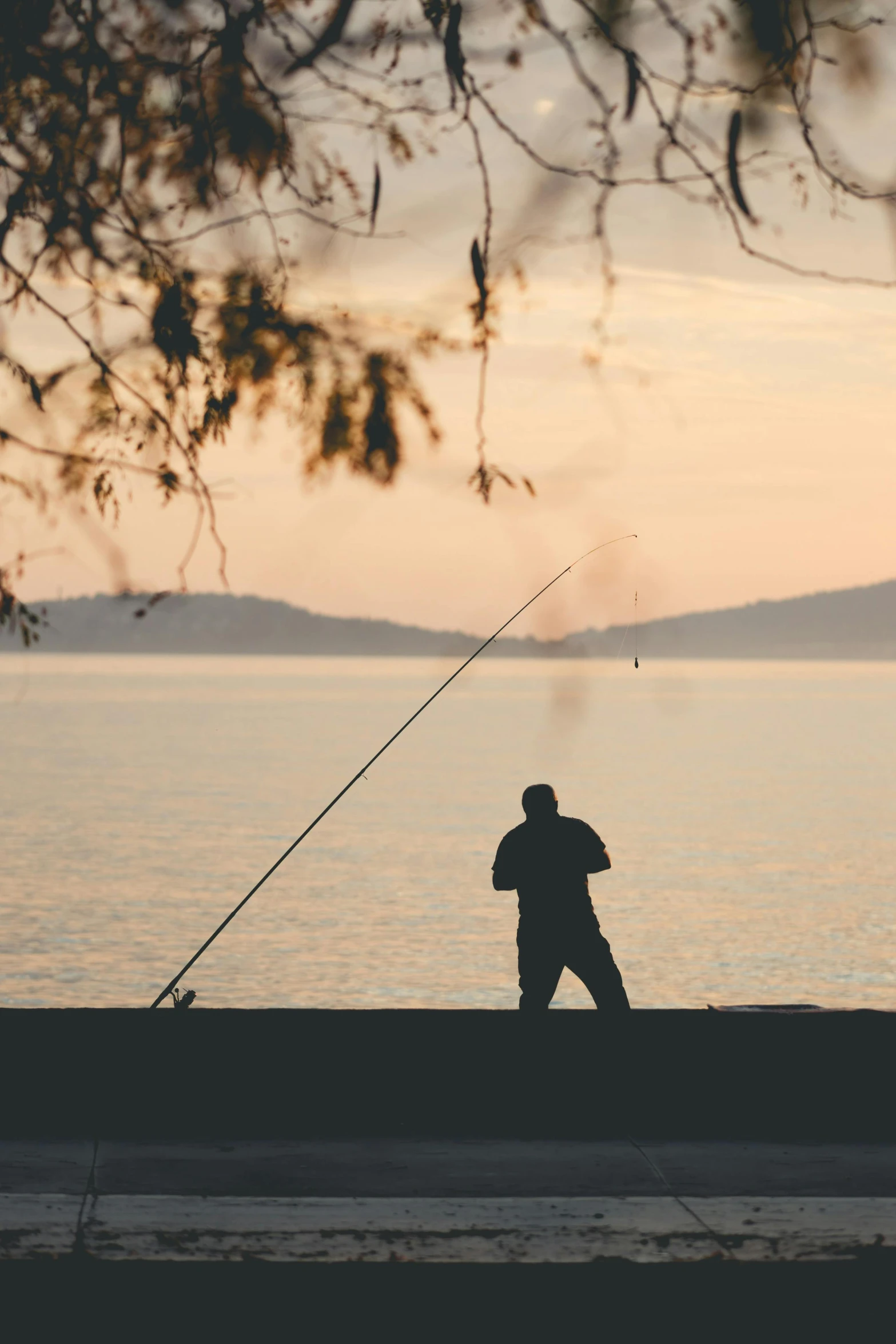 a silhouette of a man fishing in the sea at sunset