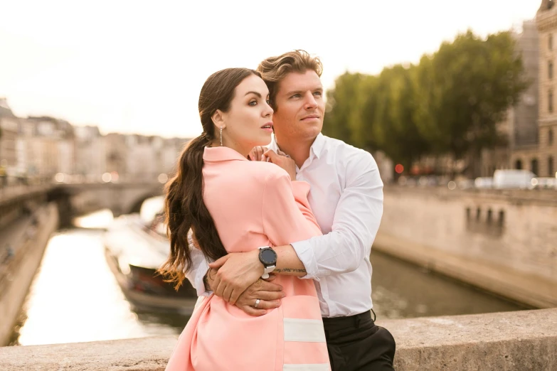 a young couple is leaning on a bridge as the sun shines down