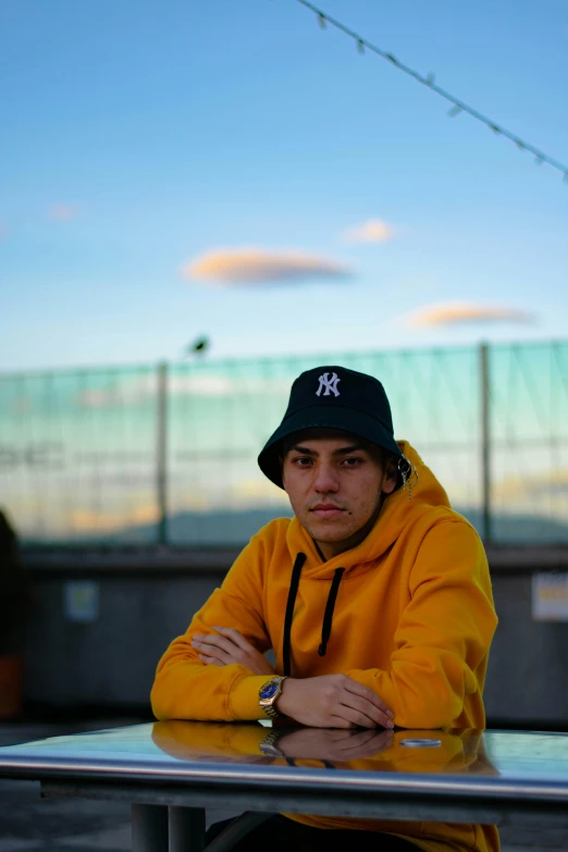 a person sitting at a table with a yellow sweatshirt on
