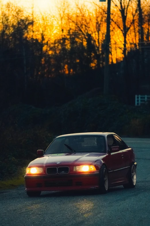 a red car driving down the road at sunset